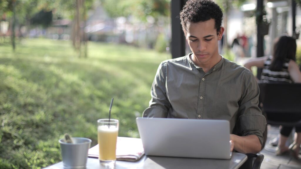 A Guy is on his laptop in an outdoor area.